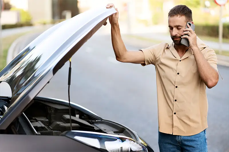 A man standing next to a car with engine problems