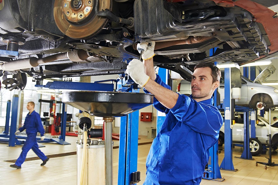 A service tech working on the underside of a vehicle