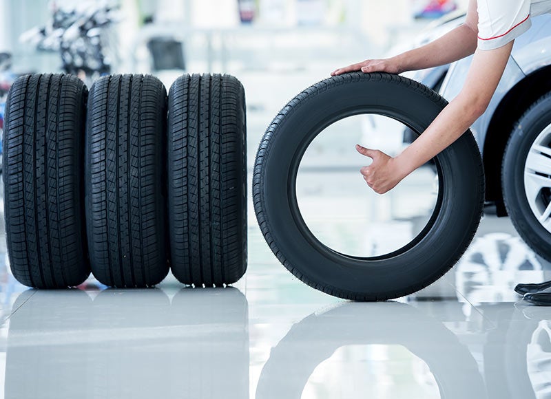 a person picking up a tire from a row of tires