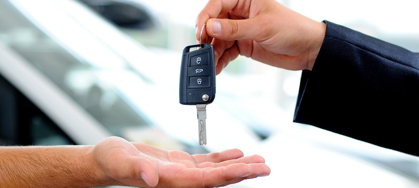 A person handing another person a car key